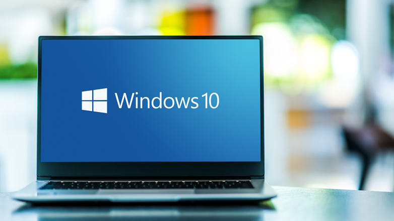 Laptop on table using Windows 10 displayed with Microsoft logo.